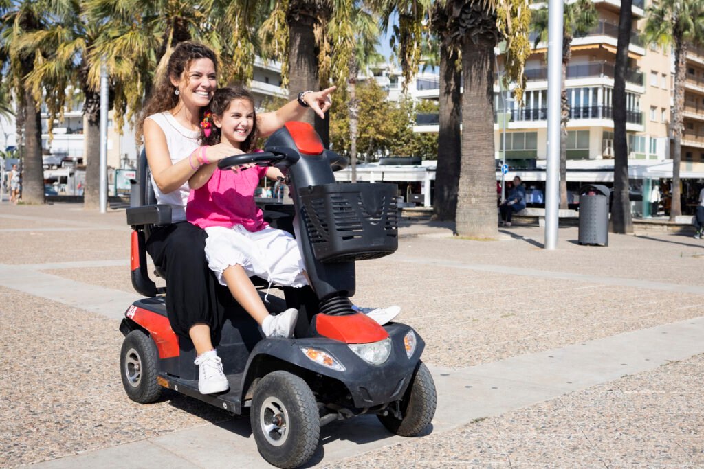 Madre e hija sonrientes sentadas en un scooter electrico